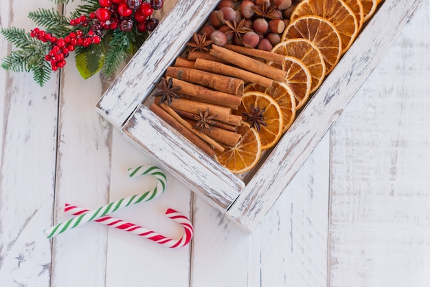 Rustikale Weihnachtskomposition mit getrockneten Orangen, Zimtstangen und Tannenzweigen in einer Holzkiste. Ansicht von oben mit Kopienraum.