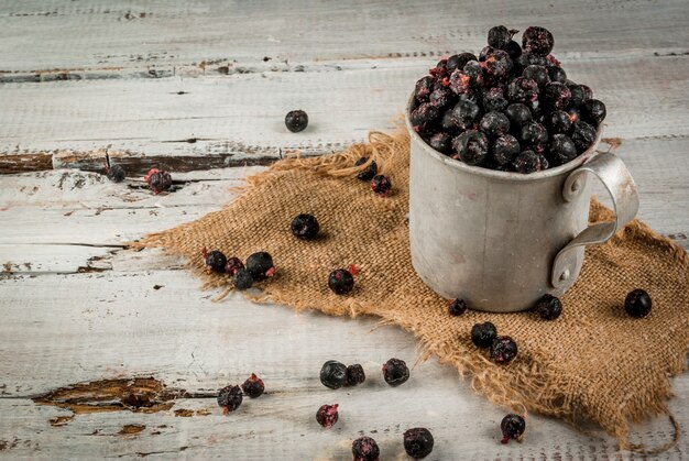 Rustikaler alter Becher mit gefrorenen Blaubeeren und Johannisbeeren