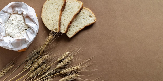 Rustikaler Küchen- oder Backwarenhintergrund mit Mehlbrot und Weizenspitzen