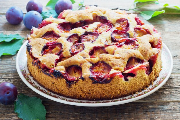 Rustikaler Pflaumenkuchen auf dunklem Holz