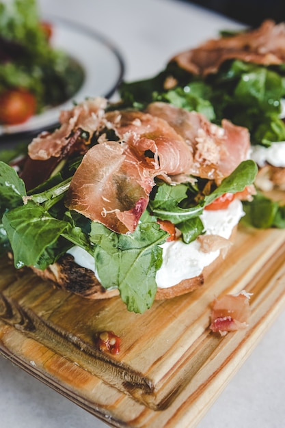 Rustikaler Toast mit Rucola, Kirschtomate, Ricotta und Schinken.