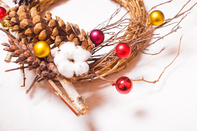 Rustikaler Weihnachtskranz aus Holz mit Baumwollblume und Tannenzapfen