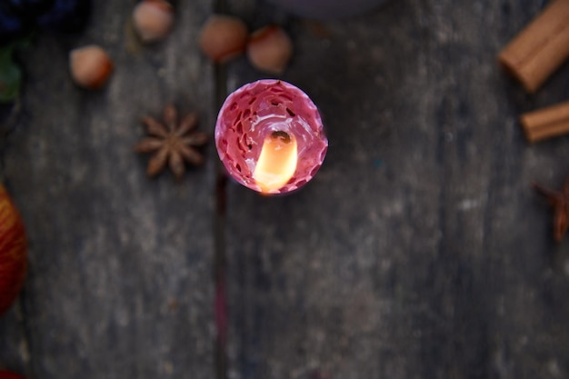 Rustikales, natürliches, gemütliches Stillleben mit Kerzenfrüchten, Haselnüssen, Anisstern und Zimtstangen Ästhetisches Herbstkonzept Rote georgine Blütenblätter Gemütliches Zuhause mit aromatischer Kerze Thanksgiving Day-Konzept