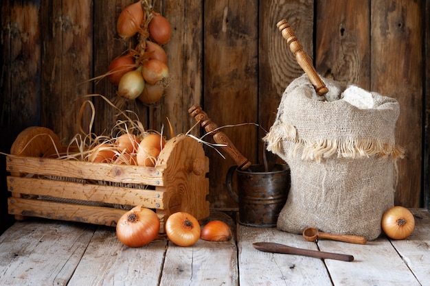 Rustikales Stillleben, Mehl, Zwiebeln, Eier und Gewürze auf einem Holztisch.