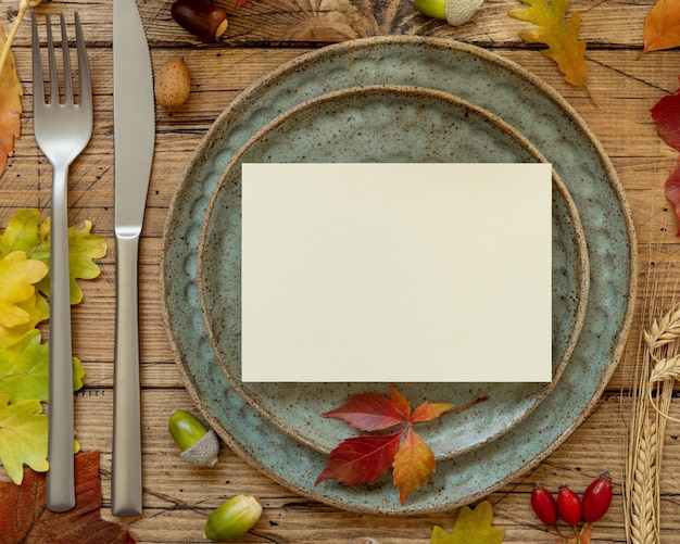 Rustikales Tischgedeck im Herbst mit leerer Karte zwischen Blättern und Beeren Draufsichtmodell