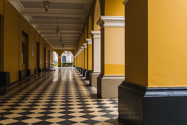 Ruta con azulejos en blanco y negro con columnas amarillas en el lado del pasaje de Santa Rosa en el centro histórico de Lima, Perú.