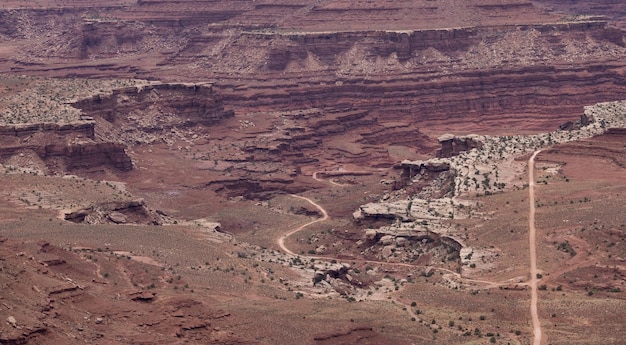 Ruta de tierra en el cañón del desierto con paisaje americano escénico y montañas de roca roja