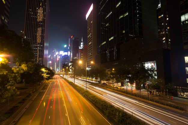 Foto rutas de luz en la carretera en medio de los edificios de la ciudad por la noche