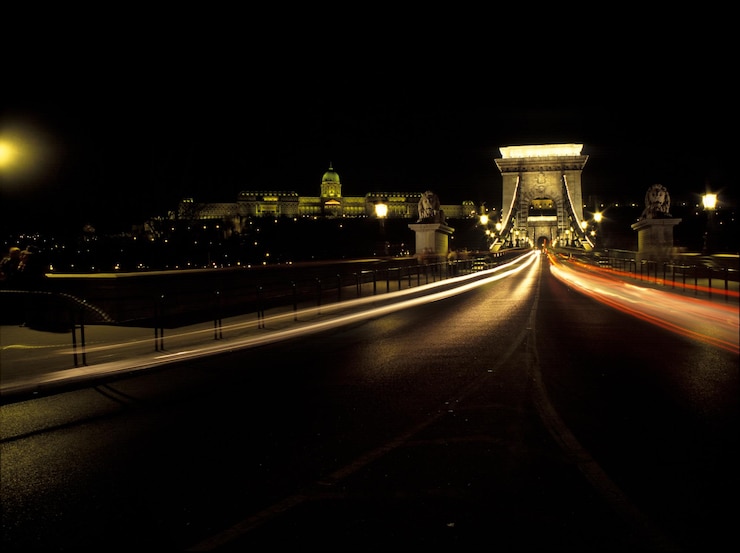 Foto rutas de luz en el puente de cadenas junto al castillo de buda contra el cielo nocturno