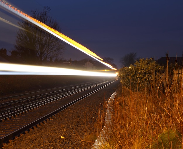 Rutas de luz en las vías del ferrocarril contra el cielo al anochecer