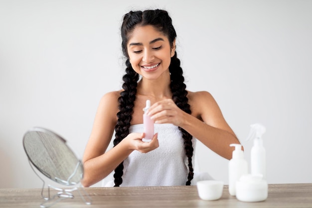 Foto rutina de belleza feliz mujer india atractiva sosteniendo botella con suero hidratante