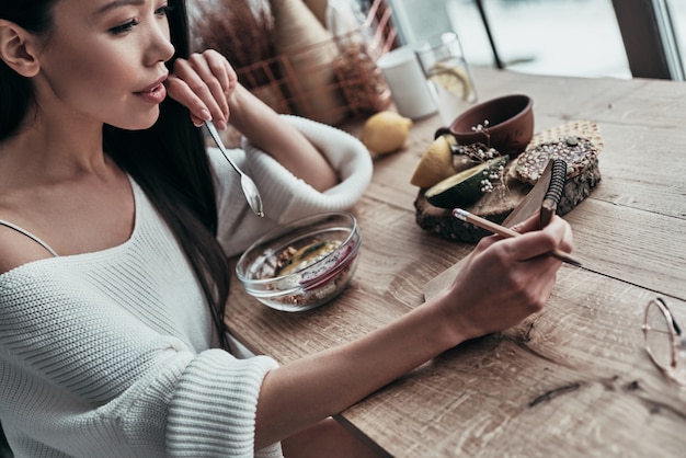 rutina diaria. Vista superior de la atractiva joven comiendo un desayuno saludable