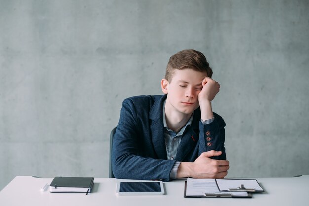 Rutina de oficina. Retrato de joven durmiendo en el lugar de trabajo, aburrido sin tarea. Copie el espacio.