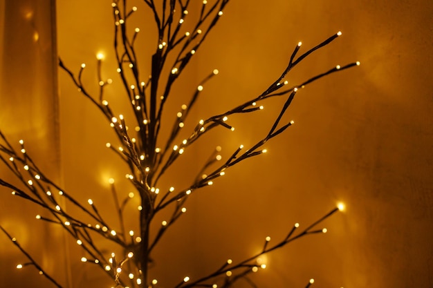Árvore brilhante minimalista elegante à noite quarto aconchegante Decoração de natal escandinava minimalista moderno preto galhos de árvores luzes douradas bokeh espaço de cópia Boas festas Iluminação festiva