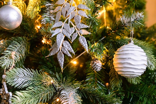 Árvore de ano novo decorada de Natal clássico. Árvore de Natal com enfeites de wite e prata, enfeites de brinquedo e bola. Apartamento de design de interiores de estilo clássico moderno. Véspera de Natal em casa.