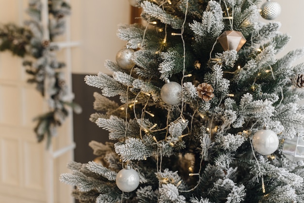 Árvore de Natal artificial em um interior brilhante com prata flores neve nos galhos. Natal.