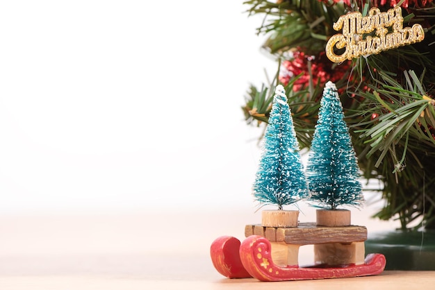 Árvore de Natal bonita decorada em um piso de madeira com fundo branco e brinquedos em branco para o conceito de design festivo fechar