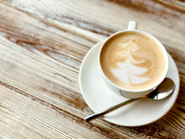 Árvore de Natal café latte art xícara de café na mesa de madeira clima de manhã de natal e ano novo