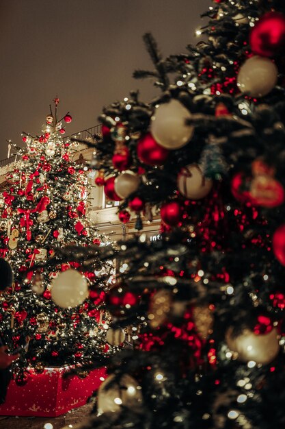 Árvore de Natal com brinquedos de Natal vermelhos em pé na rua à noite as luzes da cidade festiva