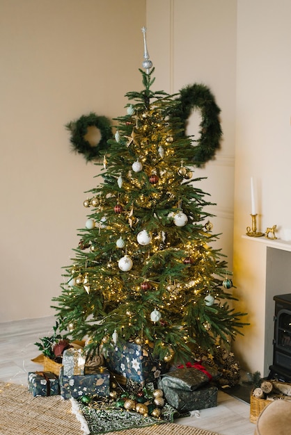 Árvore de natal com brinquedos e luzes em uma sala clássica perto da lareira