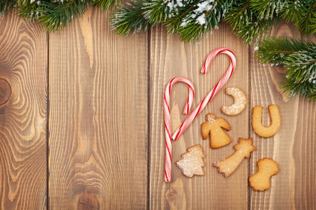 Árvore de Natal com cana-de-doce de neve e biscoitos de gengibre na placa de madeira rústica