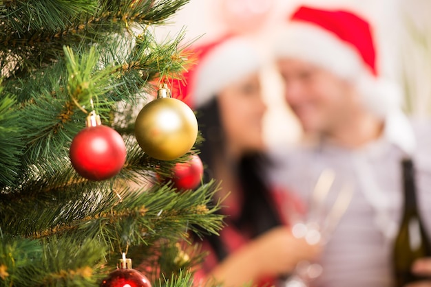 Árvore de Natal com decoração de Natal. Foco No Primeiro Plano. O plano de fundo é casal de feliz Natal.