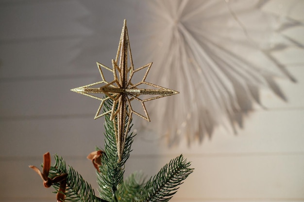 Árvore de natal com estrela vintage no topo e luzes douradas Galhos de árvores de natal decorados modernos com ornamentos elegantes fecham na sala festiva Férias de inverno tempo atmosférico