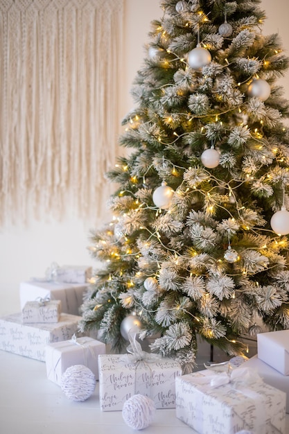 Árvore de Natal com neve branca com decoração de presentes no interior da casa de ano novo