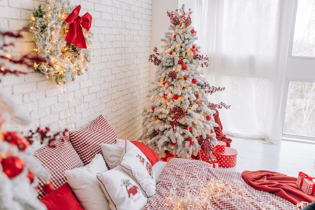 Árvore de Natal com presentes e enfeites vermelhos em um quarto bem iluminado