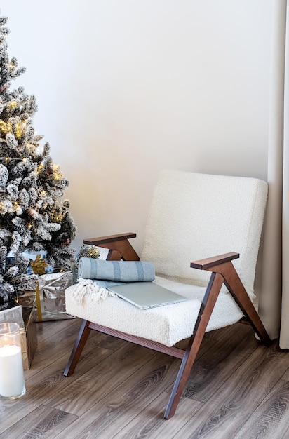 Árvore de natal com presentes e luzes e cadeira em sala iluminada e arejada