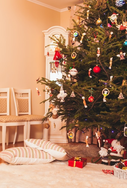 Árvore de Natal com presentes embaixo do Papai Noel e duas almofadas caídas