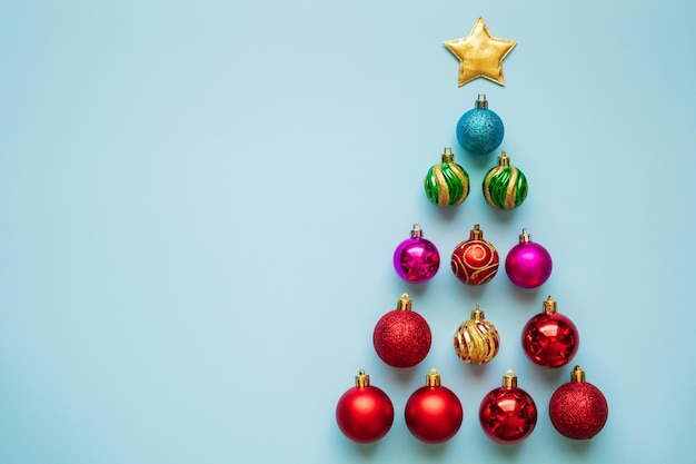Árvore de Natal de bugigangas e estrela dourada em fundo azul pastel