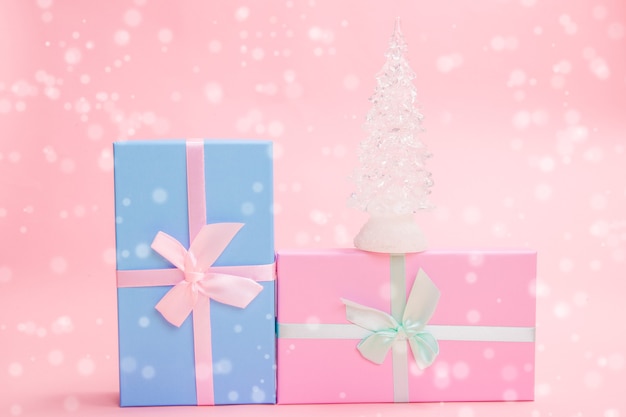 Árvore de Natal de vidro branco com presentes com laços em um fundo rosa