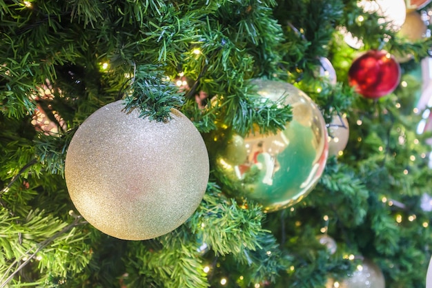 Árvore de Natal decorada com bola dourada sobre fundo de galhos de pinheiro