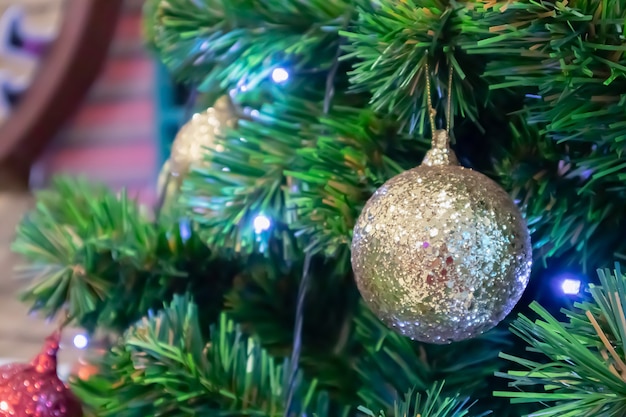 Árvore de Natal decorada com bola dourada sobre fundo de galhos de pinheiro