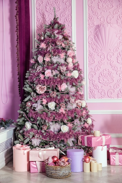 Árvore de Natal decorada com brinquedos cor de rosa. Fundo de Natal com presentes no interior da sala