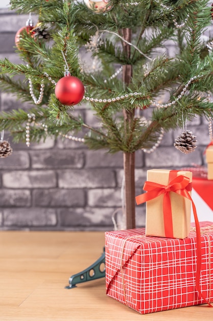 Árvore de Natal decorada com lindos presentes vermelhos e brancos embrulhados em casa com parede de tijolo preto, conceito de design festivo, close-up.