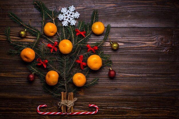 Árvore de Natal decorada com mandarins e presentes de bolas em um fundo de madeira