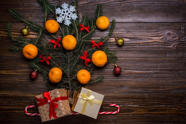 Árvore de Natal decorada com mandarins e presentes de bolas em um fundo de madeira