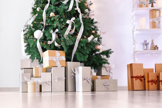 Árvore de Natal decorada com presentes em sala iluminada
