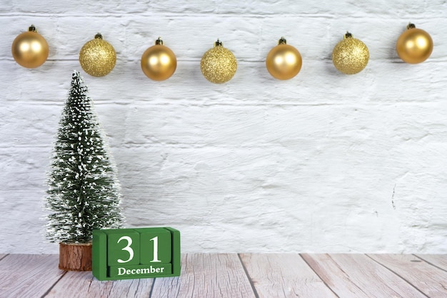 Árvore de natal decorativa e calendário de madeira no fundo da parede de tijolos brancos