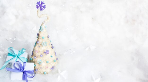 Árvore de Natal decorativa e presentes em um fundo nevado. Copie o espaço. Em branco para parabéns pelas férias de inverno