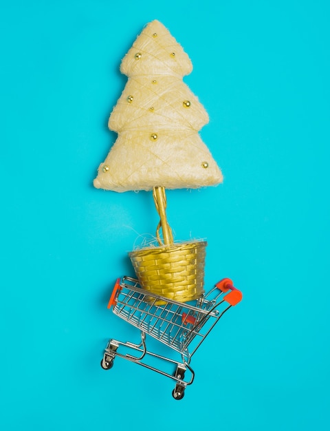Árvore de Natal dourada em um carrinho de compras em um fundo azul