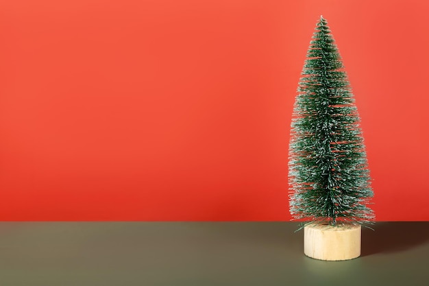 Árvore de Natal em miniatura brilhante verde sobre fundo vermelho. Copie o espaço