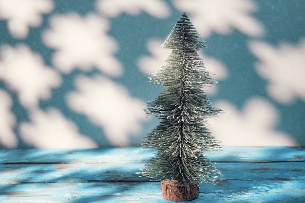Árvore de Natal em miniatura na mesa e neve caindo