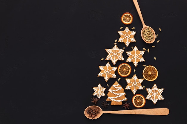 Árvore de Natal feita com biscoitos de gengibre e laranjas secas em fundo escuro, cópia espaço, vista superior