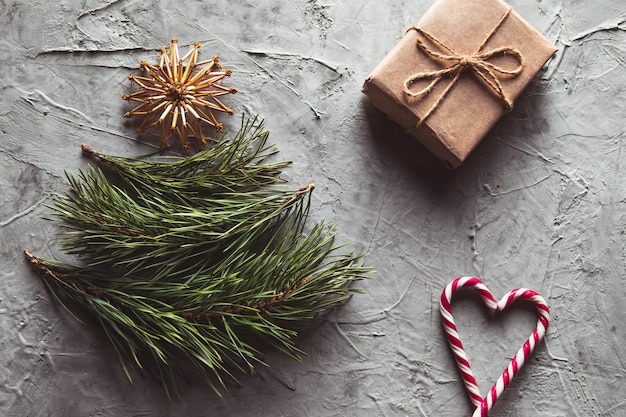 Árvore de Natal feita de folhas de pinheiro e brinquedos de palha. sobre um fundo cinza de concreto.