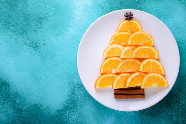 Árvore de Natal feita de rodelas de laranja em um fundo verde.