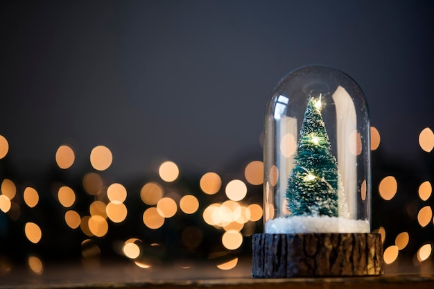 Árvore de Natal festiva dentro de um globo de neve de vidro com luzes desfocadas