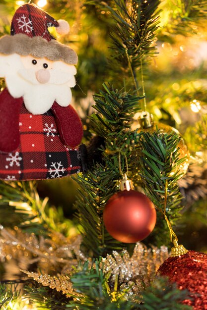 Árvore de Natal montada com enfeites. Bolas vermelhas, prata e ouro, caixas de presente, luzes, Papai Noel e outros. Foco seletivo.
